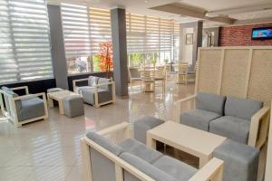 una sala de espera con sillas, mesas y ventanas en Hotel EDEA, en Korçë
