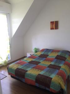 a bedroom with a bed with a colorful quilt at Voltaire in La Turballe