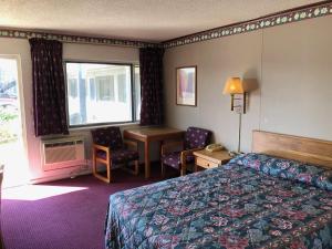 Ambassy Motel في سالينا: غرفه فندقيه بسرير ومكتب ونافذه