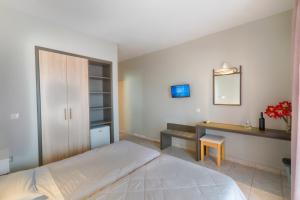 a bedroom with a bed and a desk and a mirror at Louvre Hotel in Gouvia