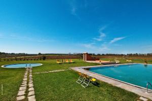 a swimming pool in a field with chairs in the grass at Podere Del Gesso in Tarquinia