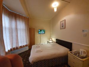 a hotel room with a bed and a television at The Handforth Lodge in Handforth