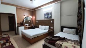 a hotel room with two beds and a mirror at Fiesta Inn Hotel & Resorts Multan in Multan