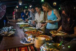 a group of people holding plates of food at a buffet at Ammarin Bedouin Camp in Wadi Musa