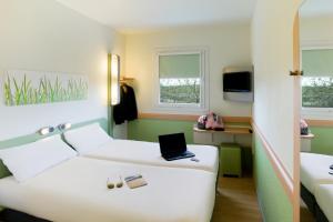 Habitación de hotel con cama con ordenador portátil en Ibis Budget Bilbao Arrigorriaga en Arrigorriaga