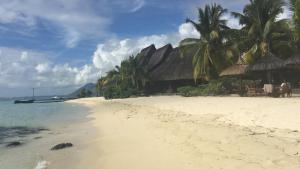 a beach with palm trees and a boat in the water at Otium in Coteau Raffin
