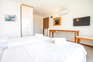 two beds in a room with a tv on the wall at Medimar Hotel in Kaş