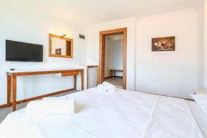 a white bedroom with a bed and a tv at Medimar Hotel in Kaş