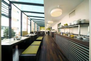 um restaurante com mesas longas, bancos e janelas em Boutiquehotel am Stadtgarten em Friburgo em Brisgóvia