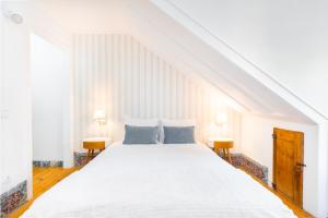 una camera bianca con un grande letto bianco con due tavoli di WHome | Sé Skyline Apartment a Lisbona