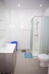 a white bathroom with a shower and a toilet at BRUMA HOSTEL in Ponta Delgada +90 photos