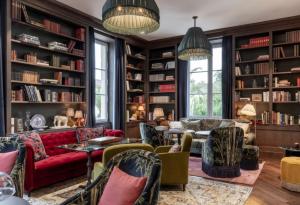 - un salon avec une bibliothèque et un canapé rouge dans l'établissement La Maison d'Estournel, à Saint-Estèphe