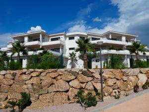 a large white building behind a stone wall at Résidence Les Jardins du Fort in Porticcio