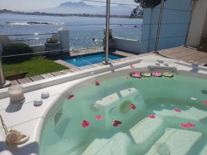 a jacuzzi tub with a view of the ocean at Westbank Private Beach Villa, 4 Bedrooms, Private pool, on the Beach! in Gordonʼs Bay