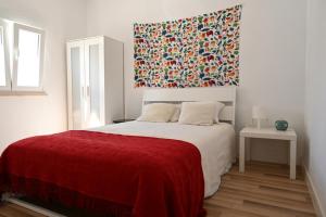 1 dormitorio con 1 cama grande con manta roja en Casa dos Clérigos, en Alcácer do Sal