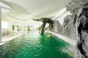 an infinity pool with a waterfall in a house at Hotel Saalbacher Hof in Saalbach-Hinterglemm