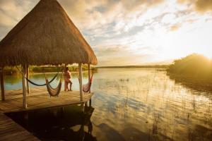 un niño parado en una hamaca en un muelle en el agua en Eco Hotel Casa Corazón Bacalar, en Bacalar