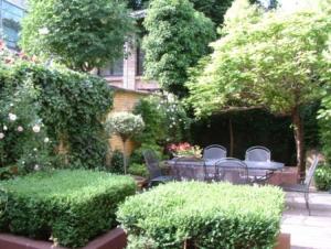 um jardim com mesa, cadeiras e arbustos em B&B Sparrow's Nest em Gante