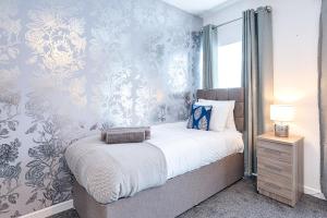 a bedroom with a bed with blue and silver wallpaper at Ideal location in Morriston! in Swansea