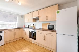 a kitchen with wooden cabinets and a white refrigerator at Ideal location in Morriston! in Swansea