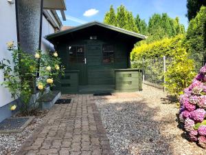 a green shed with a brick walkway in front of a house at Ferienhaus _Auf dem Bremsberg_ in Glücksburg