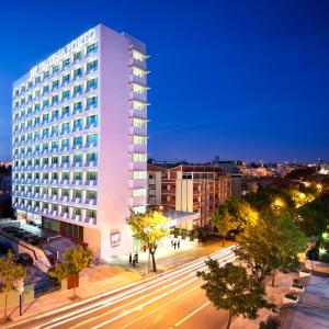 un edificio blanco alto en una calle de la ciudad por la noche en HF Ipanema Porto en Oporto