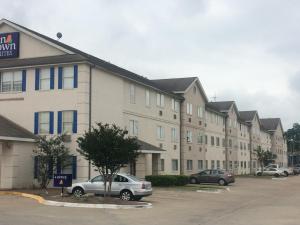 um grande edifício de apartamentos com carros estacionados num parque de estacionamento em InTown Suites Extended Stay Select Houston TX - BrookHollow em Houston