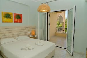 a bedroom with a white bed and a balcony at Saint Nicholas Beach Resort in Dassia +130 photos