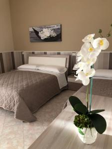 - une chambre avec un lit et un vase avec des fleurs blanches dans l'établissement Tortora House, à Scafati