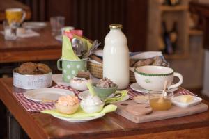 einen Tisch mit Tassen und Teller mit Essen und einer Flasche Milch in der Unterkunft Bed & Breakfast Dvorec in Petrovče