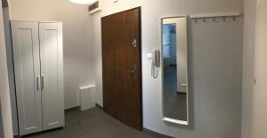 ein Badezimmer mit einer Holztür und einem Spiegel in der Unterkunft APARTAMENT ŚMIAŁEGO 9 in Świdnica