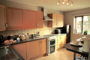 cocina con armarios de madera y horno con fogones en Hambleton House, en Catterick Camp