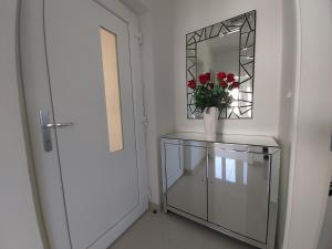 a mirror and a vase with flowers on a glass cabinet at Apartment Seaside Mireja in Kaštela