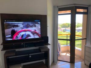 a living room with a tv and a window at Apartamento frente à praia! in Florianópolis