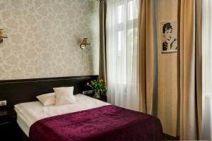 a bedroom with a bed with a purple blanket and a window at Hotel Racibor in Racibórz +89 photos