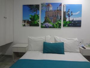 a bedroom with a bed with three paintings on the wall at Almaviva Casa Hotel in Medellín