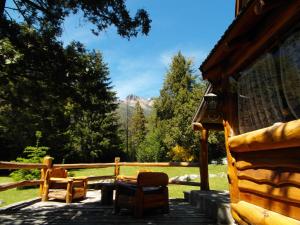 un patio con sillas, una valla y árboles en La Cabaña de Juan en Villa Traful