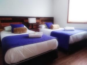 a room with three beds with blue and white sheets at Hostal Buenavista Patagonia in Punta Arenas