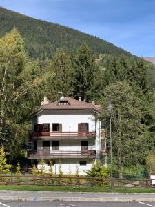 a large white house in the middle of trees at White Rock in Ponte di Legno