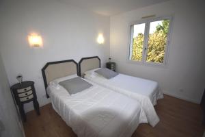 Duas camas num quarto branco com uma janela em VILLA PECH DE DURAND VILLENEUVE SUR LOT em Villeneuve-sur-Lot