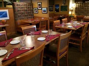 a restaurant with wooden tables and chairs with red napkins at Soldotna Inn in Soldotna