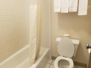 a bathroom with a toilet and a bathtub with a shower curtain at TravelStar Inn & Suites in Colorado Springs