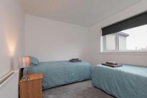 a bedroom with two beds and a window at Grampian Serviced Apartments - Park View in Elgin