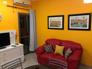 Un sofá rojo en una sala de estar con paredes amarillas. en Departamento Guly, en Villa María