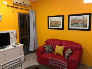 un sofá rojo en una sala de estar con paredes amarillas en Departamento Guly en Villa María