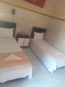 Cette chambre comprend 2 lits avec des draps et des oreillers blancs. dans l'établissement Pondok Sunrise 2, à Gili Trawangan