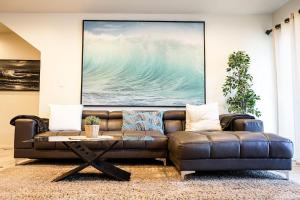 a brown leather couch in a living room with a painting at Newport Beach House 1 blk to beach and 25 min to Disney in Newport Beach