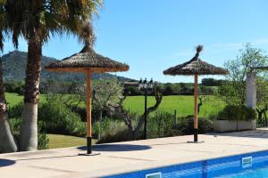 dos sombrillas de paja sentadas junto a una piscina en Finca Ses Cases Noves, en Sant Llorenç des Cardassar