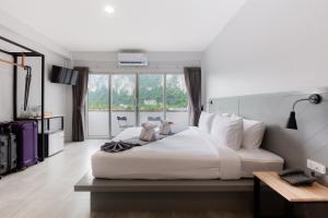 um quarto com uma cama branca e uma grande janela em Monotel Aonang em Praia de Aonang
