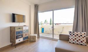 a living room with a couch and a television and a balcony at Apartment Club Playa Flores Torremolinos in Torremolinos
